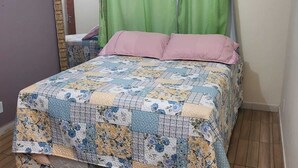 Une chambre avec un lit, des rideaux verts, un miroir et un tapis moelleux.