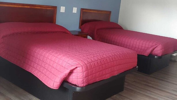 Habitación de hotel con dos camas y cabeceros de madera, y una pared azul.