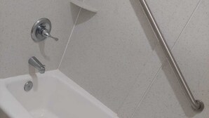Una bañera blanca con una barra de apoyo y una toalla.