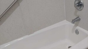 Una bañera blanca con un asidero, un cabezal de ducha y un perchero para toallas.