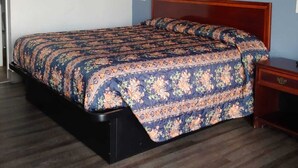 Un dormitorio con una cama, cabecera de madera y una mesita de noche.