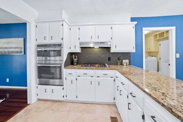 A kitchen with white cabinets, a stainless steel oven, a gas stove, and a granite countertop. - Serene & Spacious Family Retreat w/ Pool. Park and St. Francis Hospital Nearby. (Tulsa)