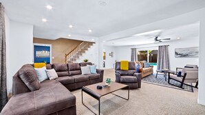 A spacious living area with a large sectional sofa, a coffee table, and a staircase leading to another level.