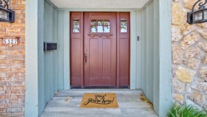 A front door with a doormat, a mailbox, and a stone wall.
