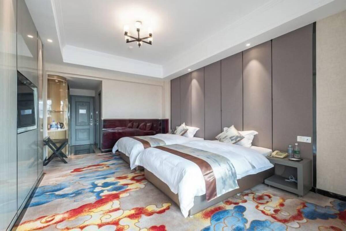 A modern hotel room with a large bed, a desk with a phone, and a nightstand.