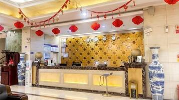 A hotel reception area with a counter, chairs, and decorative elements.