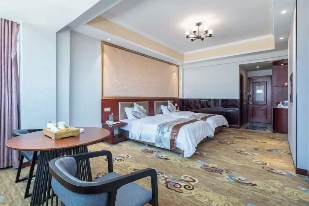 A hotel room with a large bed, a round dining table, and a separate seating area with chairs.