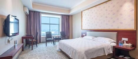 Une chambre d’hôtel avec un lit, une télévision, un bureau et une chaise.