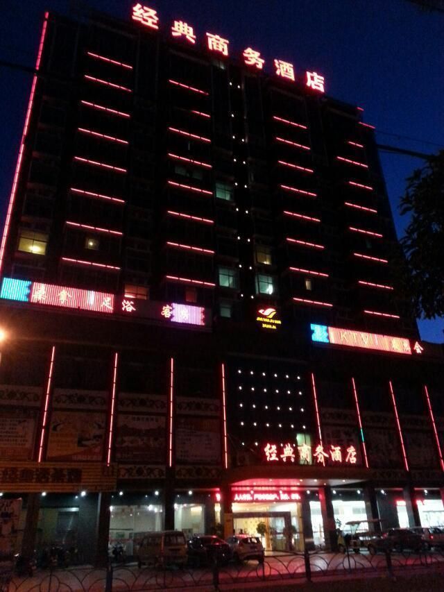 Een meerlaags gebouw met verlichte reclameborden en diverse winkels op de begane grond.