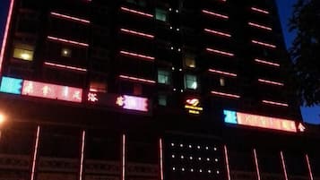 A multi-story building with illuminated signage and multiple ground-level commercial spaces.