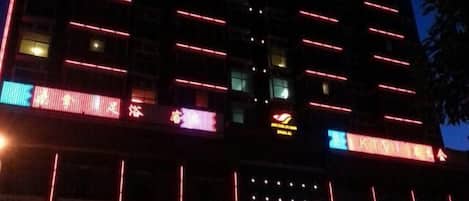 A multi-story building with illuminated signage and multiple ground-level commercial spaces.