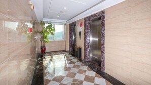 A hotel lobby with a checkered floor, marble walls, and an elevator. - Jingdian Hotel (Nan'an)
