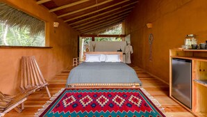 Una habitación de madera con una cama, una mesita pequeña y un banco.