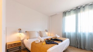 Siististi järjestetty hotellihuone, jossa on sänky, yöpöydät ja ikkuna, jossa on verhot.
