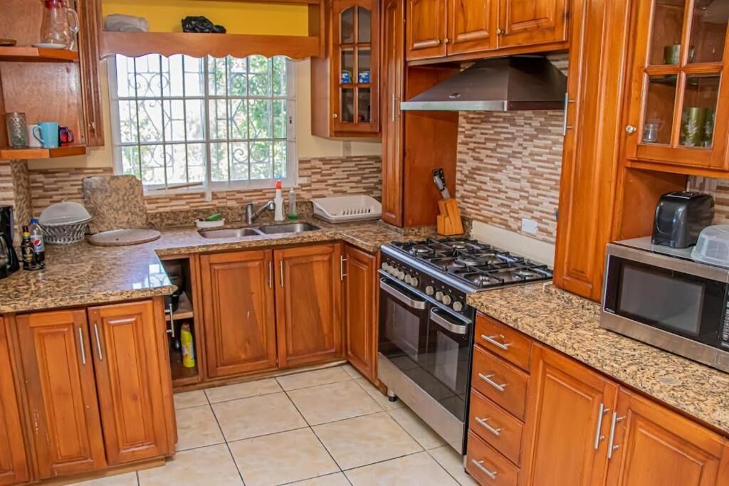 A kitchen with wooden cabinets, granite countertops, a gas stove, an oven, and a microwave.