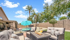 Un patio al aire libre con una chimenea, sillones de descanso y una piscina.