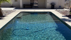 Ein rechteckiger Pool mit klarem Wasser, umgeben von einer gefliesten Terrasse.