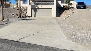 Ein eingeschossiges Haus mit Garage und Auffahrt, auf der ein schwarzer SUV geparkt ist.