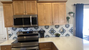 Eine Küche mit Holzschränken, Edelstahlgeräten und einer Fliesenrückwand mit Muster.
