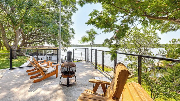 Eine Terrasse mit Sitzgelegenheiten im Freien, einem Kaminofen und Seeblick.