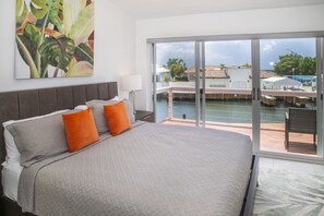A hotel room with a large bed, a view of a pool, and a balcony. - 247B South Finger Waterfront Villa, Jolly Harbour (Jolly Harbour)