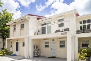 A two-story building with a flat roof, numbered 247B, featuring a front entrance, a small porch, and a balcony on the upper floor. - 247B South Finger Waterfront Villa, Jolly Harbour (Jolly Harbour)