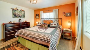 Ein Schlafzimmer mit einem großen Bett, einem Schminktisch, einem Nachttisch und einem Fenster mit Vorhängen.