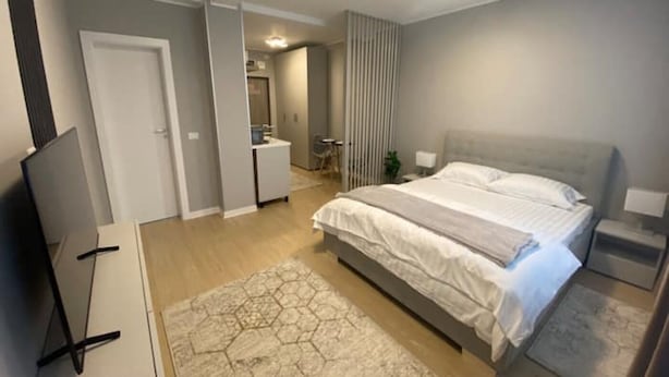 Un dormitorio moderno con una cama grande, un escritorio y una televisión.