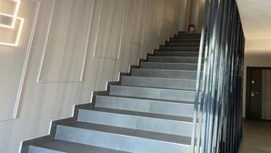 Una escalera moderna con un diseño elegante, paredes de tonos claros y barandilla de metal.