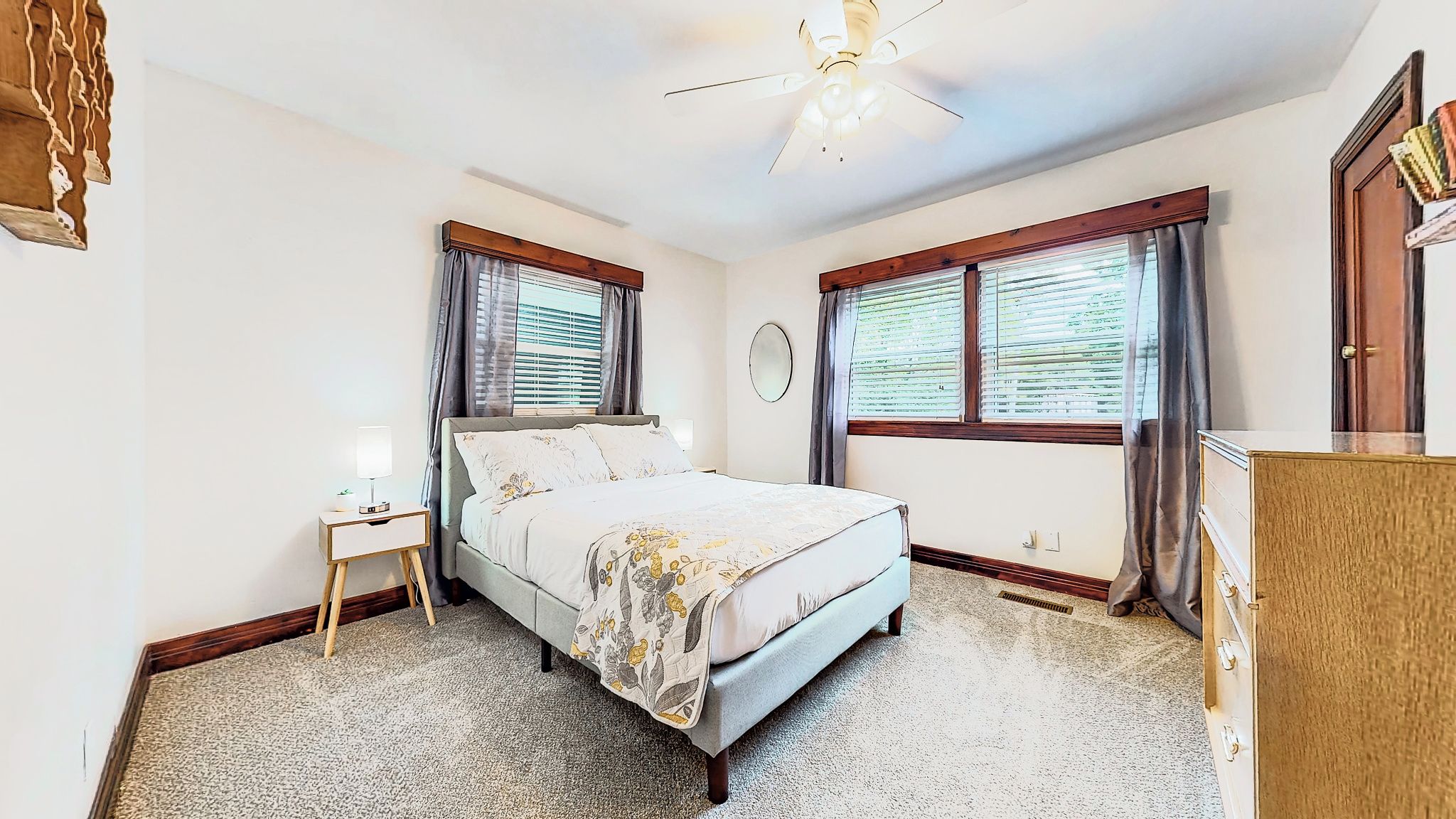 Une chambre à coucher avec un lit, une table de chevet, une lampe et un ventilateur de plafond.