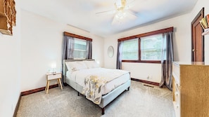 Une chambre à coucher avec un lit, une table de chevet, une lampe et un ventilateur de plafond.