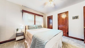 Une chambre à coucher avec un lit, une table de chevet, une lampe et un ventilateur de plafond.