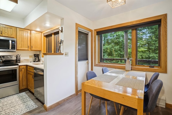 Una cocina moderna con armarios de madera, microondas, estufa y un comedor con mesa y sillas.