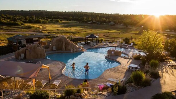 Zona de piscina con sillones de descanso y un pabellón, rodeada de paisaje natural.