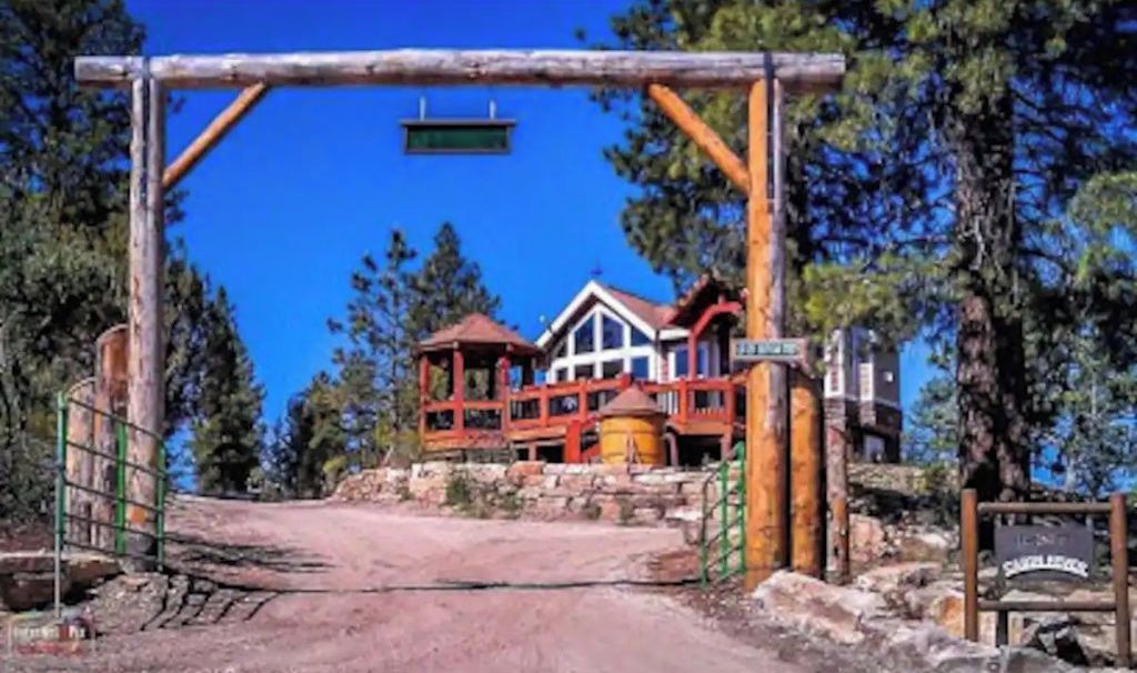 Un rustico lodge con struttura in legno, un sentiero sterrato che vi conduce e un cartello con la scritta 'Saddleback'.