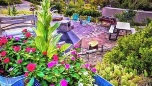 Un patio con un hogar a leña de piedra, mobiliario exterior y plantas en macetas.