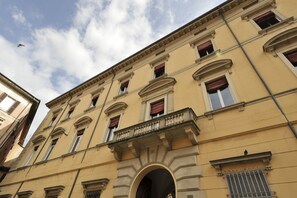 A multi-story building with classical architecture, featuring arched windows and a central balcony.