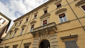 Ein mehrstöckiges Gebäude mit klassischer Architektur, mit Bogenfenstern und einem zentralen Balkon.