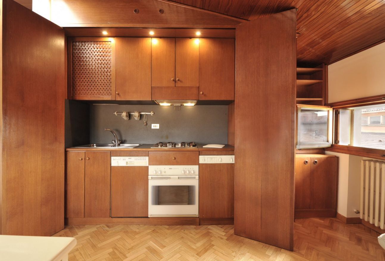 Una cocina compacta con armarios de madera, horno empotrado y pileta.