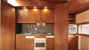 Eine kleine Küche mit Holzschränken, einem Einbauofen und einem Spülbecken.
