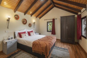 Camera da letto con soffitto in legno, un letto con biancheria da letto bianca e una coperta marrone, un comodino, un armadio e luci a parete.