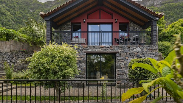 Ein zweistöckiges Steinhaus mit rotem Dach und einem Balkon.