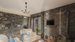 Ein gemütliches Wohnzimmer mit Steinwand, Kamin, einer Couch und einem Couchtisch.