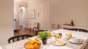 Un'area pranzo con un tavolo apparecchiato per la colazione, con frutta, una pianta e un piatto di cibo.