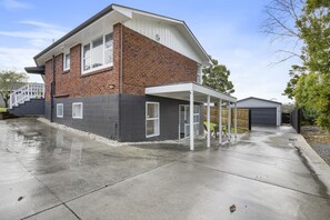 A two-story brick house with a covered patio and a garage.