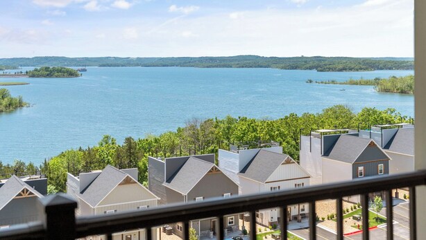 A view of a lake with a residential area in the foreground, featuring houses with sloped roofs and a clear sky. - Spacious, Family Friendly Condo with Lake View - The Majestic at Table Rock (Branson)