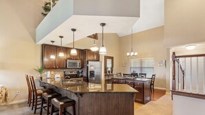 A spacious kitchen with a large island, dark wood cabinets, stainless steel appliances, and pendant lighting. - Spacious, Family Friendly Condo with Lake View - The Majestic at Table Rock (Branson)