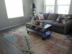 A living room with a sofa, a coffee table with plants, a lamp, and a colorful rug. - Zion Fence Line - Walk to Trailhead  - Secluded (Orderville)