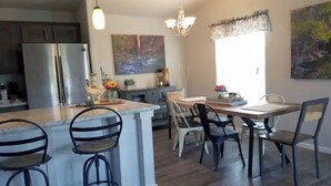 A modern kitchen with a central island, bar stools, and a dining area with chairs. - Zion Fence Line - Walk to Trailhead  - Secluded (Orderville)