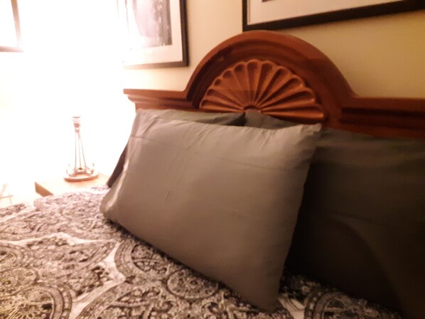 Uma cama com um edredom estampado e duas almofadas.
